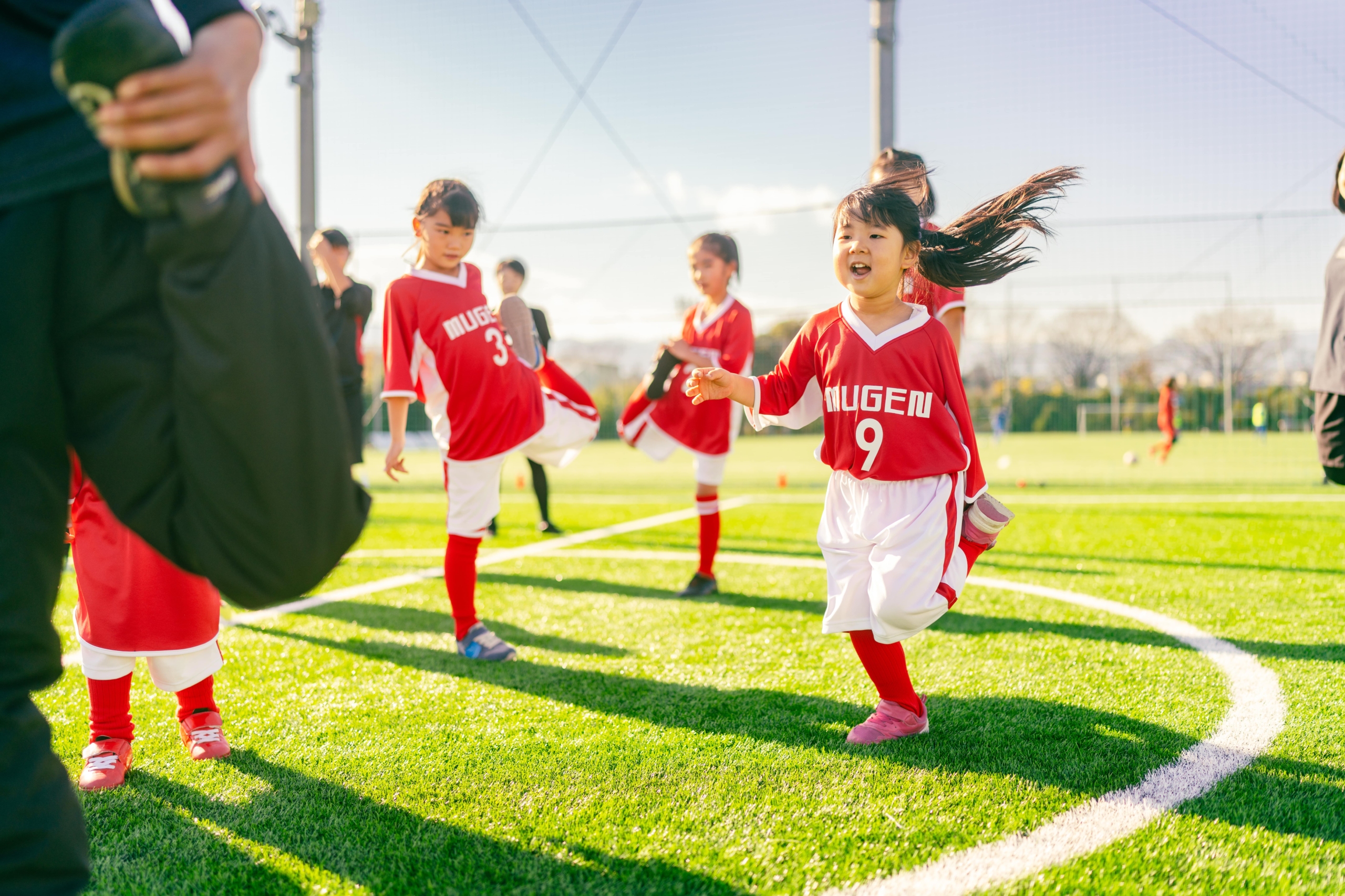 iStock-1360033145-min Group of girls in red sports uniform in a football field